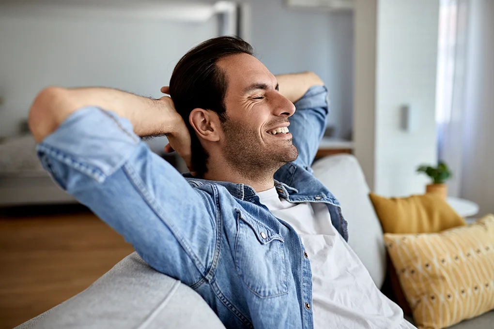 young-happy-man-with-hands-head-relaxing-sofa-home